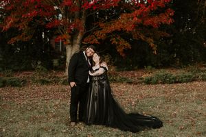 A tender moment captured between a couple in formal wear under red maple trees.