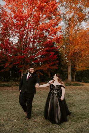 Playful couple shares joyful moments during their autumn photoshoot with red maple trees.