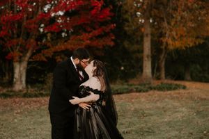 Two people share an intimate dance moment beneath trees with stunning fall colors.