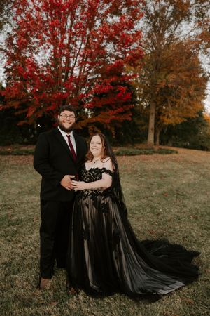A romantic autumn portrait session featuring a couple in black formal attire against colorful fall foliage.