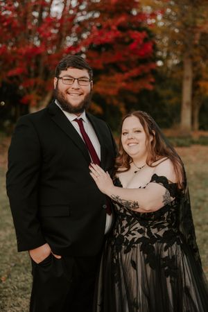 A couple shares happy moments during their autumn photoshoot with vibrant fall colors in the background.