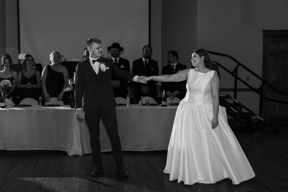 A black and white photo shows a bride and groom dancing together at their wedding reception.