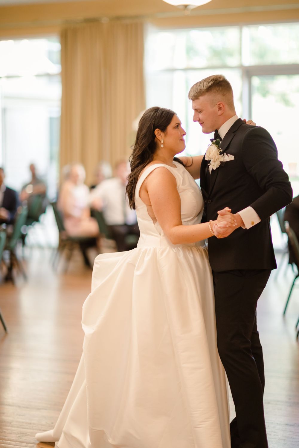 Couple shares a romantic dance moment at their wedding reception on a polished ballroom floor.