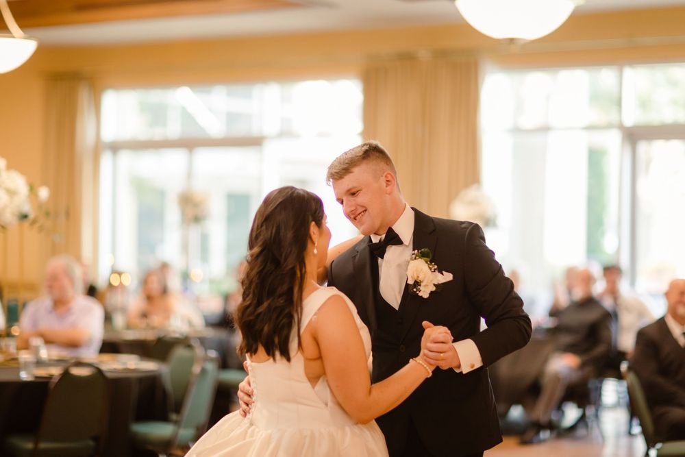 A couple shares a romantic dance together at an elegant wedding reception venue with warm lighting.