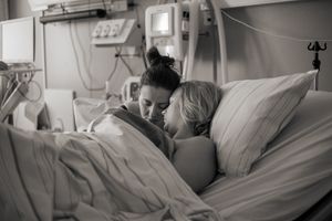 Förlossningsfotografering på BB Stockholm. Två mammor myser i sängen efter förlossningen och ser med förundran på sin nyfödda bebis