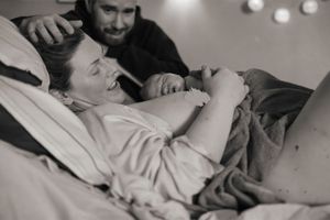 Förlossningsfotografering på BB Stockholm. En bild på den nya familjen tagen i profil. Pappan ser överväldigad och känslosam ut.