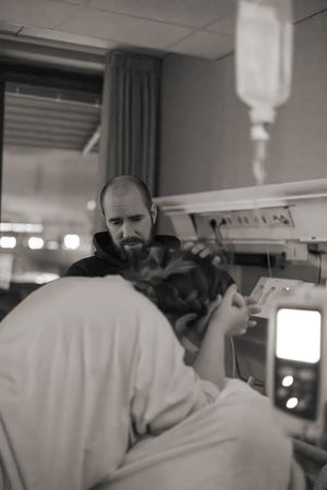 Förlossningsfotografering på BB Stockholm. Kvinnan tar värkar på knän i sängen, pappan ser orolig på.
