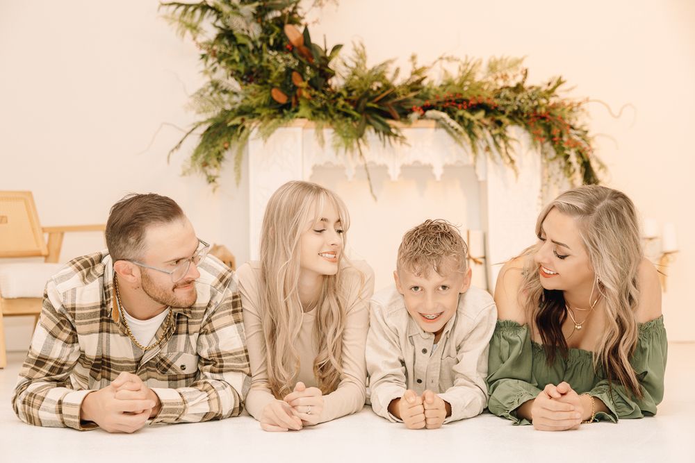Christmas family pictures of a family of 4 sitting down in an indoor studio in Greeley Colorado. pictures of 2 kids and 2 parents smiling