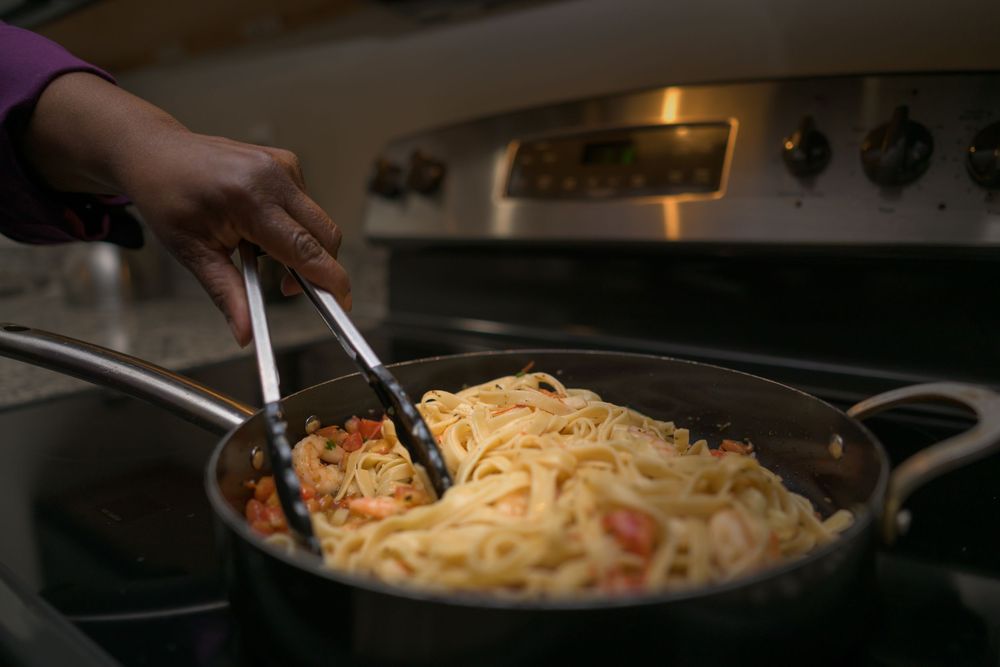 A series of cooking shots showing pasta being prepared in a pan with sauce and ingredients.