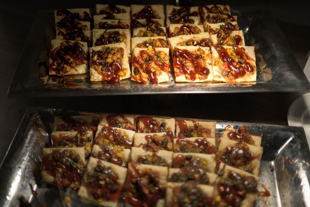Rows of freshly baked pecan pie bars cooling on metal baking racks in a commercial kitchen setting.