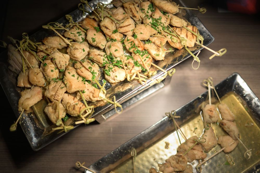 Grilled chicken and vegetables on skewers arranged on a wooden cutting board with fresh herbs.