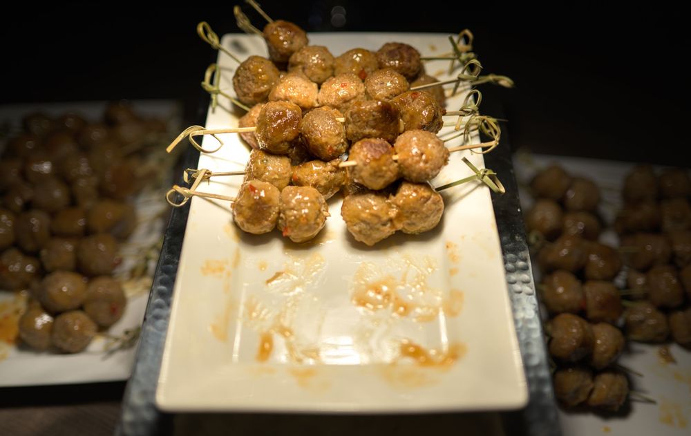 Freshly cooked meatballs displayed on a white rectangular plate with garnish.
