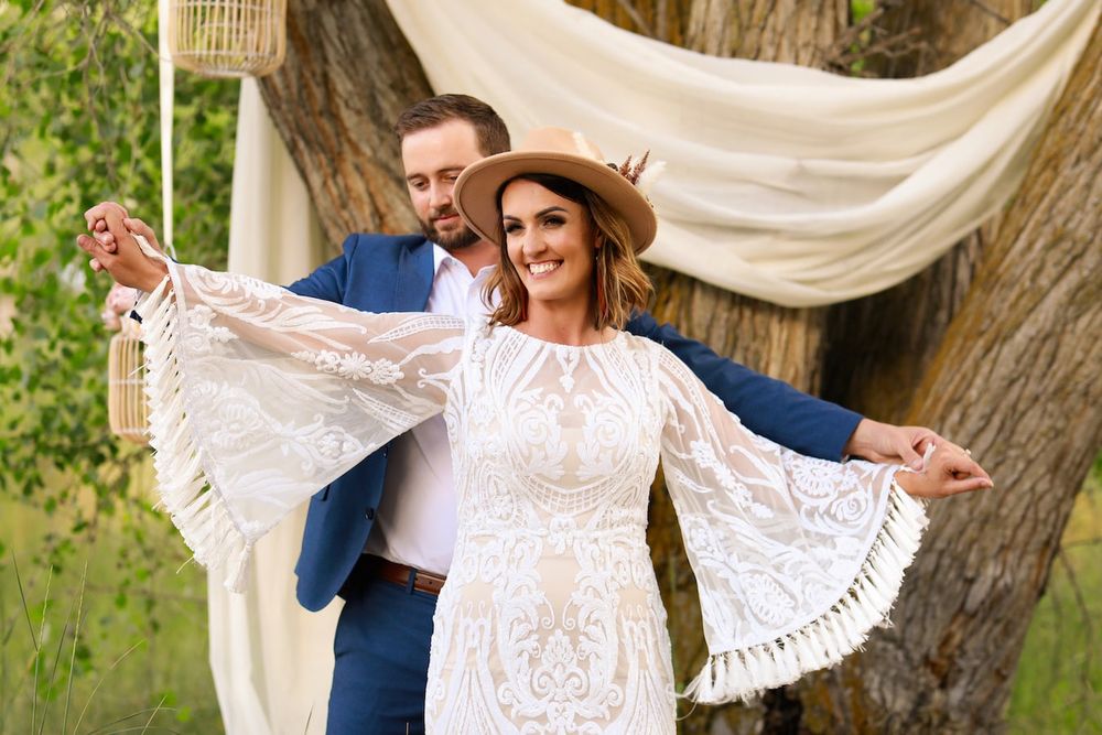 Couple embraces and dances together outdoors with flowing white lace veil creating romantic movement in the sunlight.