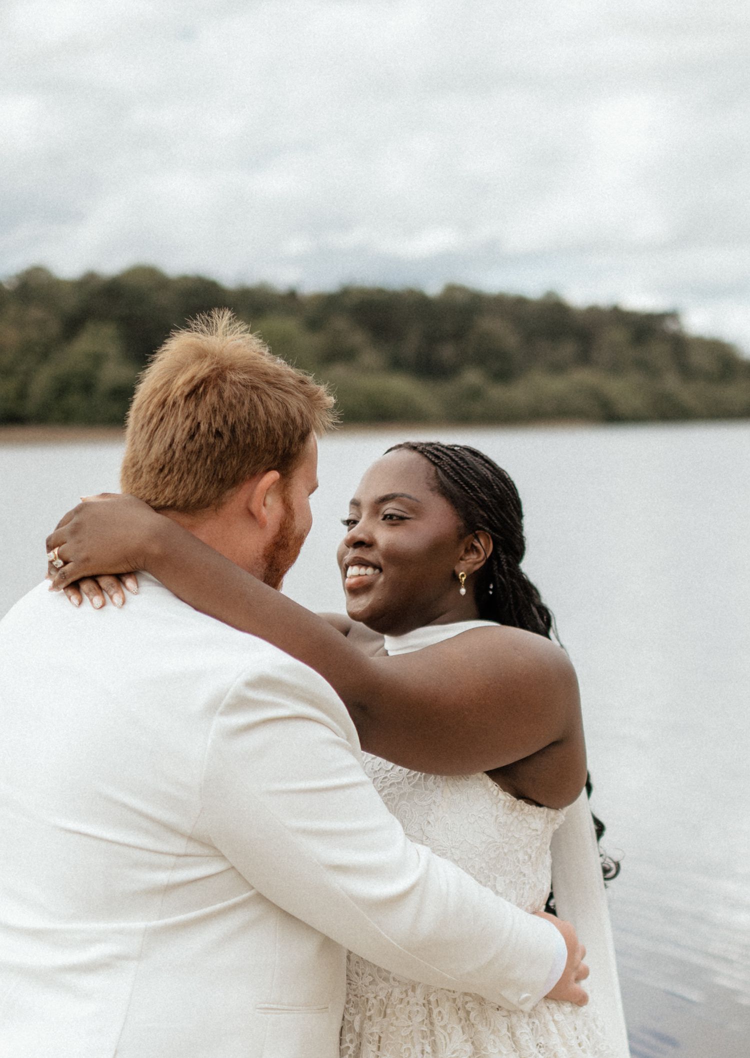 A couple in wedding attire shares joyful moments by a serene lakeside, captured in a series of candid photographs.