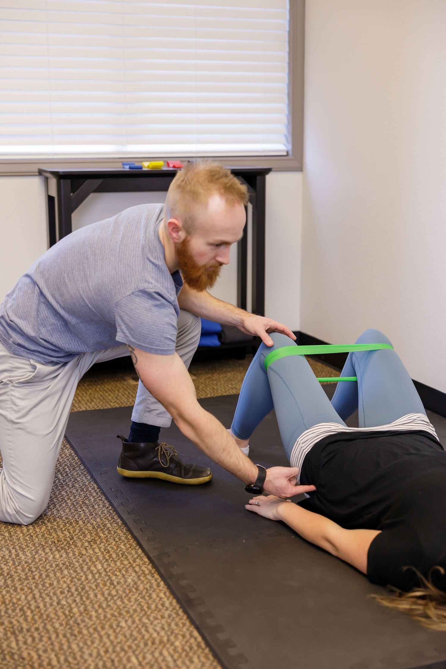 chiropractor branding photo in Sumner, WA wellness health man educating woman how to use resistance bands for hip health and alignment