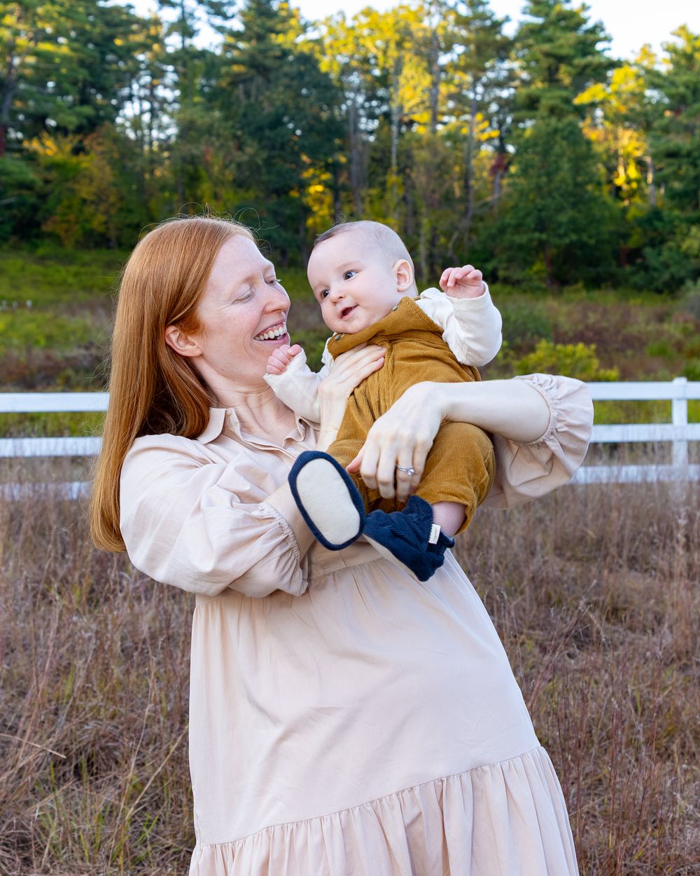 A series of joyful moments captured in a field with fall foliage and white fencing in the background in Sudbury, MA.
