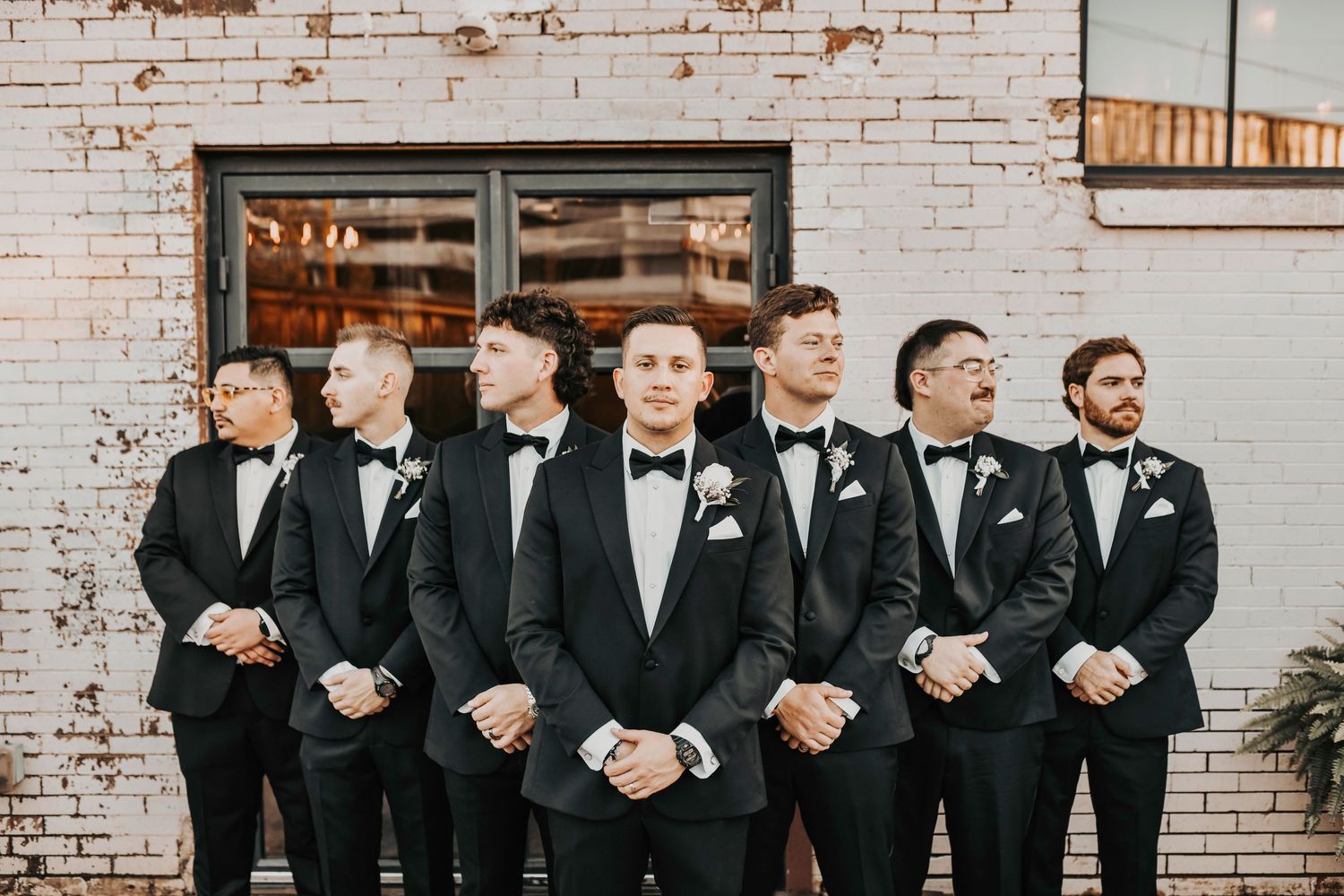 Candid groomsmen and bridesmaids celebrating at sunset, warm light and industrial textures creating a modern Dallas aesthetic.