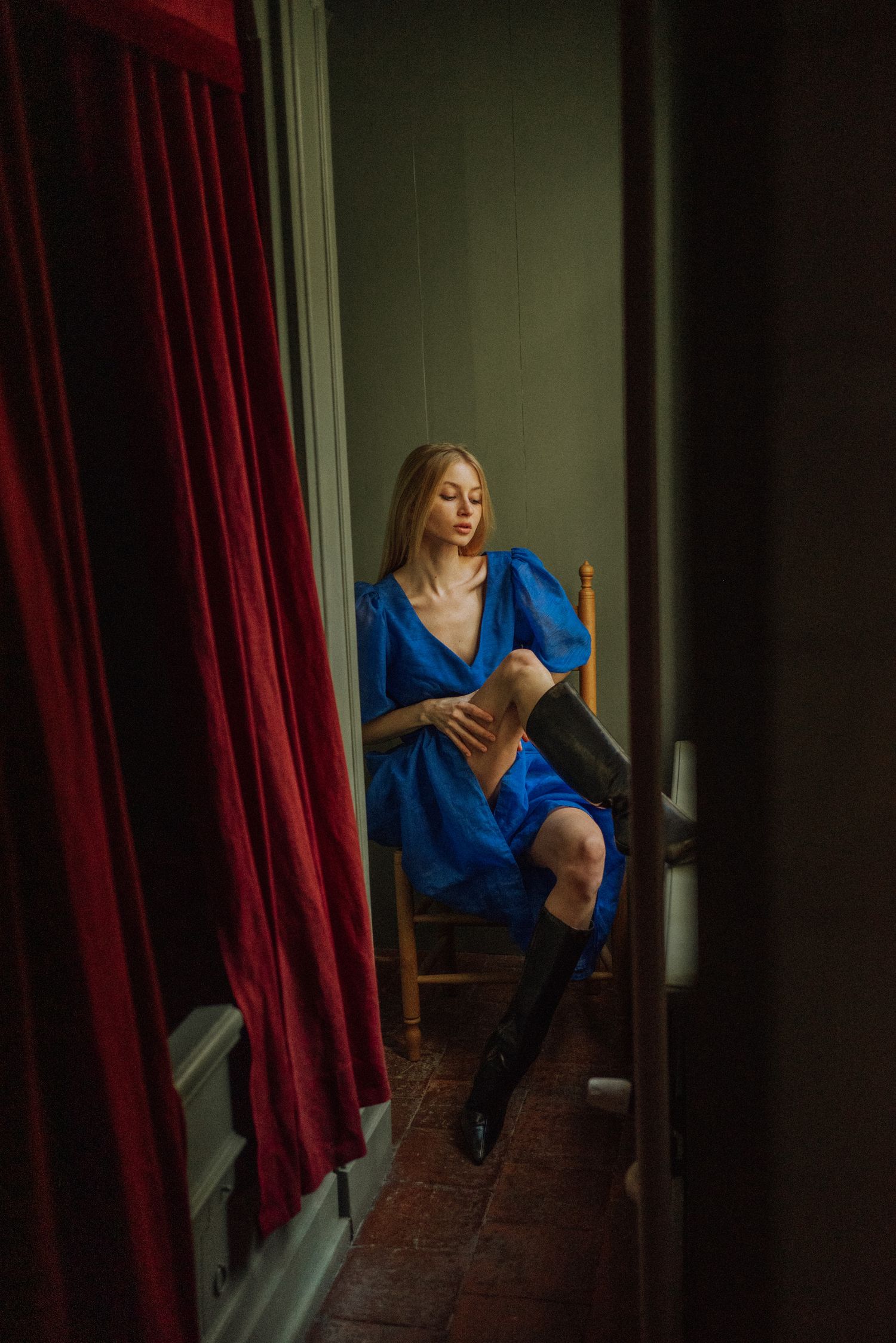Dramatic scene with red curtains and moody lighting in a vintage interior setting.