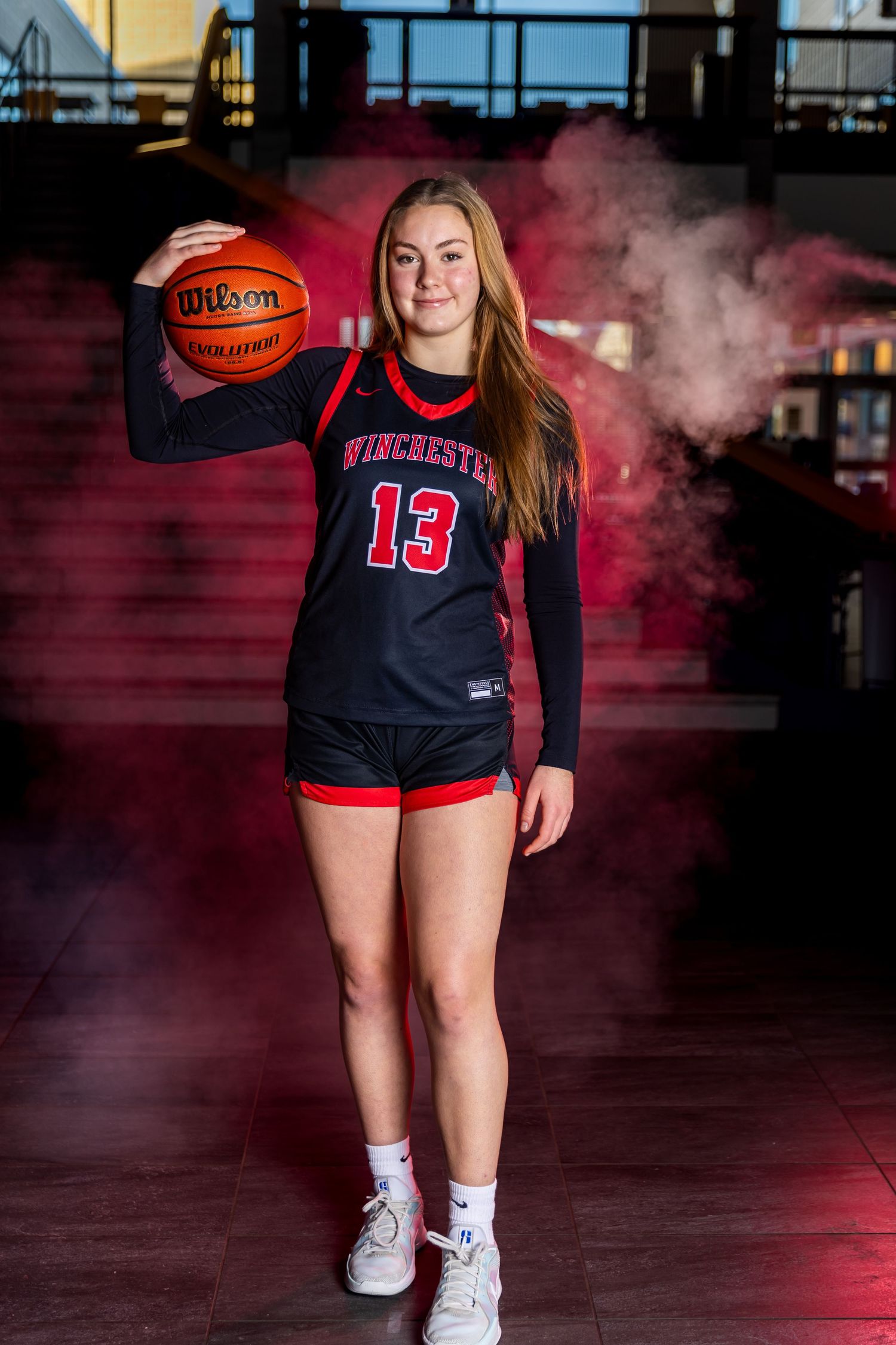 Basketball player in Westchester #13 jersey stands with Wilson basketball amid dramatic red smoke effects.