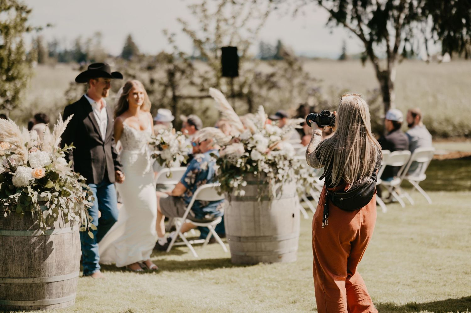 Wedding photographer capturing bride and groom with floral decorations in outdoor setting.