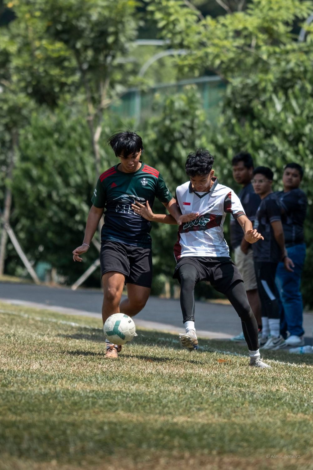 Two soccer players competing for ball control during a match on a sunny field.