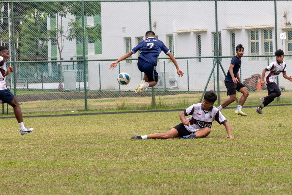 Players competing in an intense ultimate frisbee match with one player leaping high to catch the disc.
