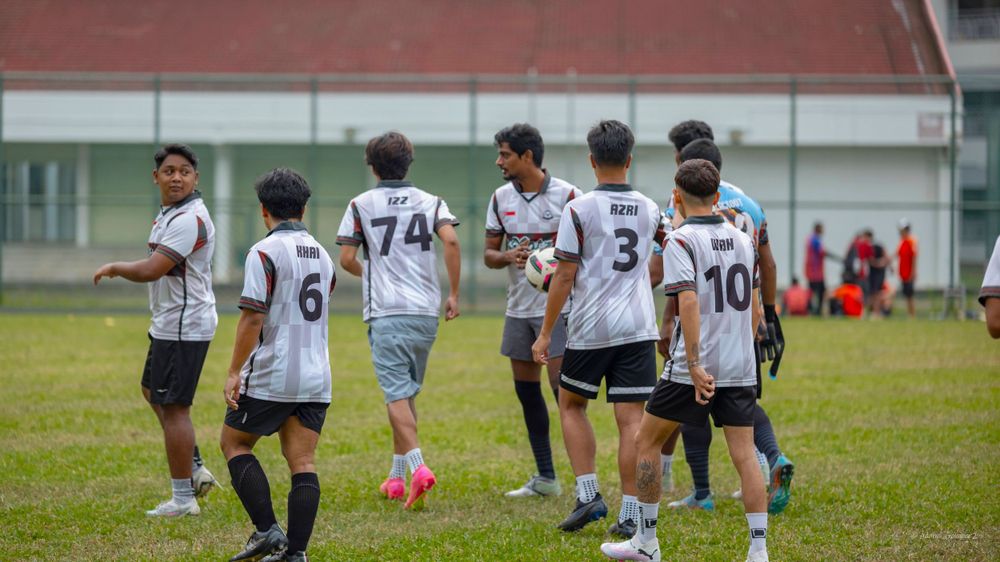 Soccer team players in white jerseys gathering on a grass field during practice or game break.