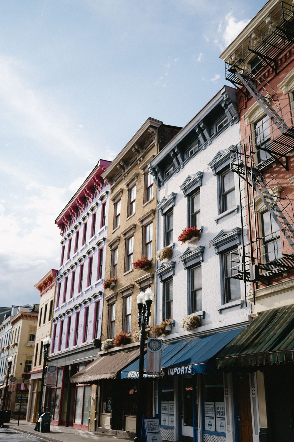 Colorful historic buildings with fire escapes and ornate architecture line a city street.
