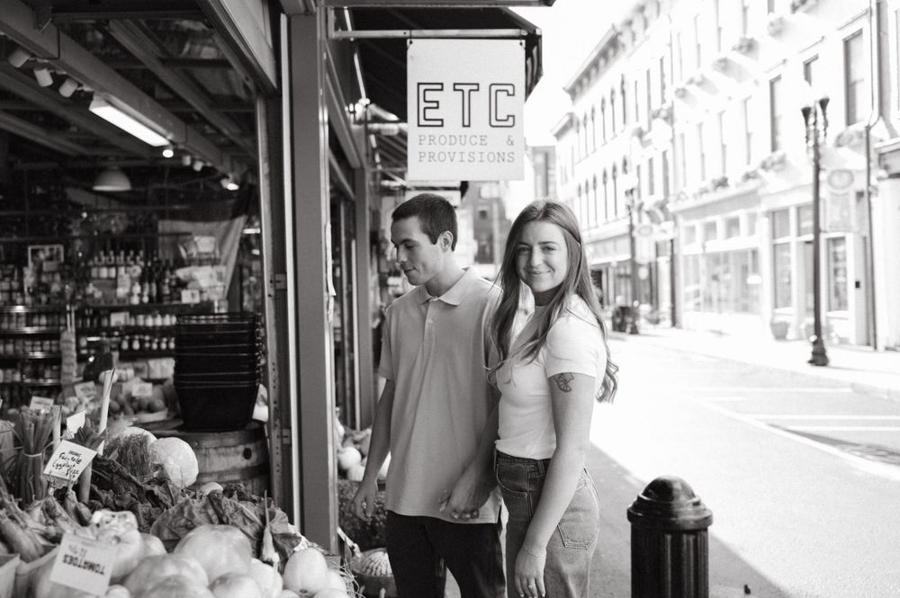 Couple standing outside ETC Provisions store with fresh produce displays.