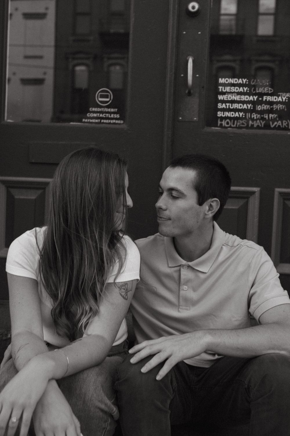 A couple shares an intimate conversation while sitting together in black and white.