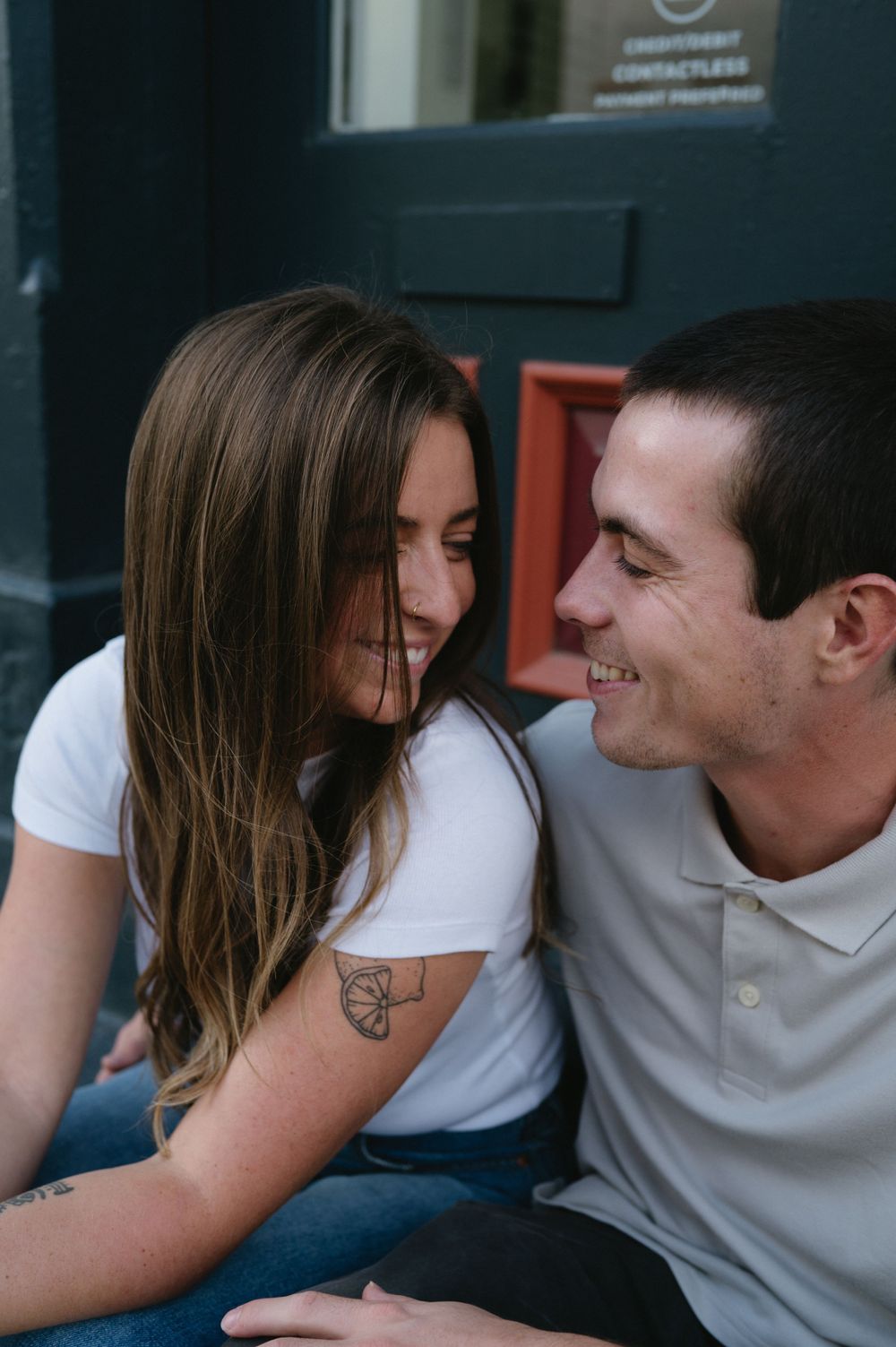 A couple shares a tender moment while sitting close together outdoors.
