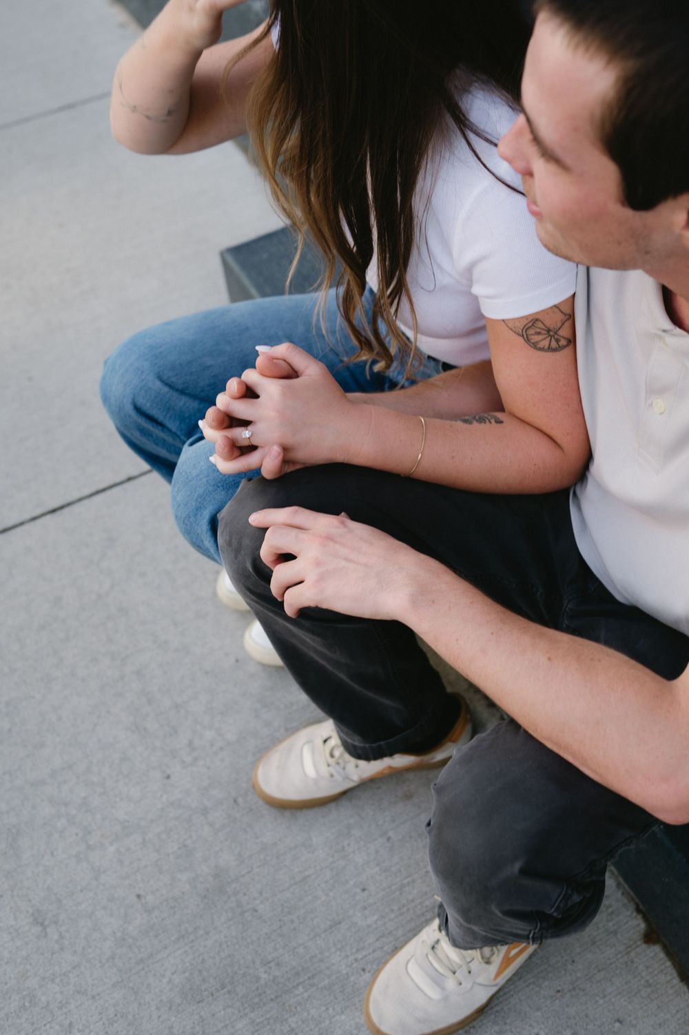 A close-up shot of hands clasped together while sitting on concrete steps.