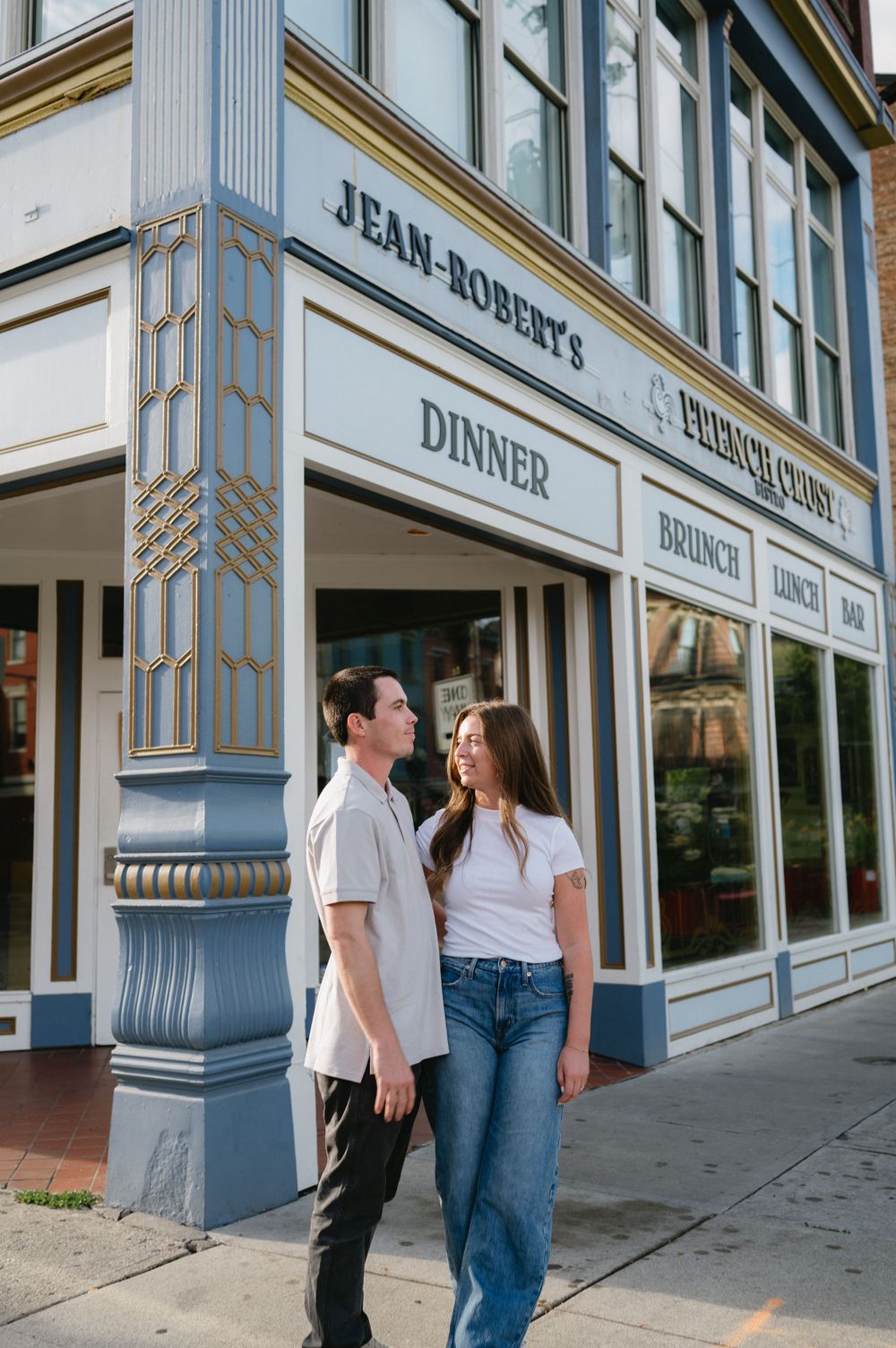 Couple standing outside Jean-Robert's restaurant storefront with classic architectural details.