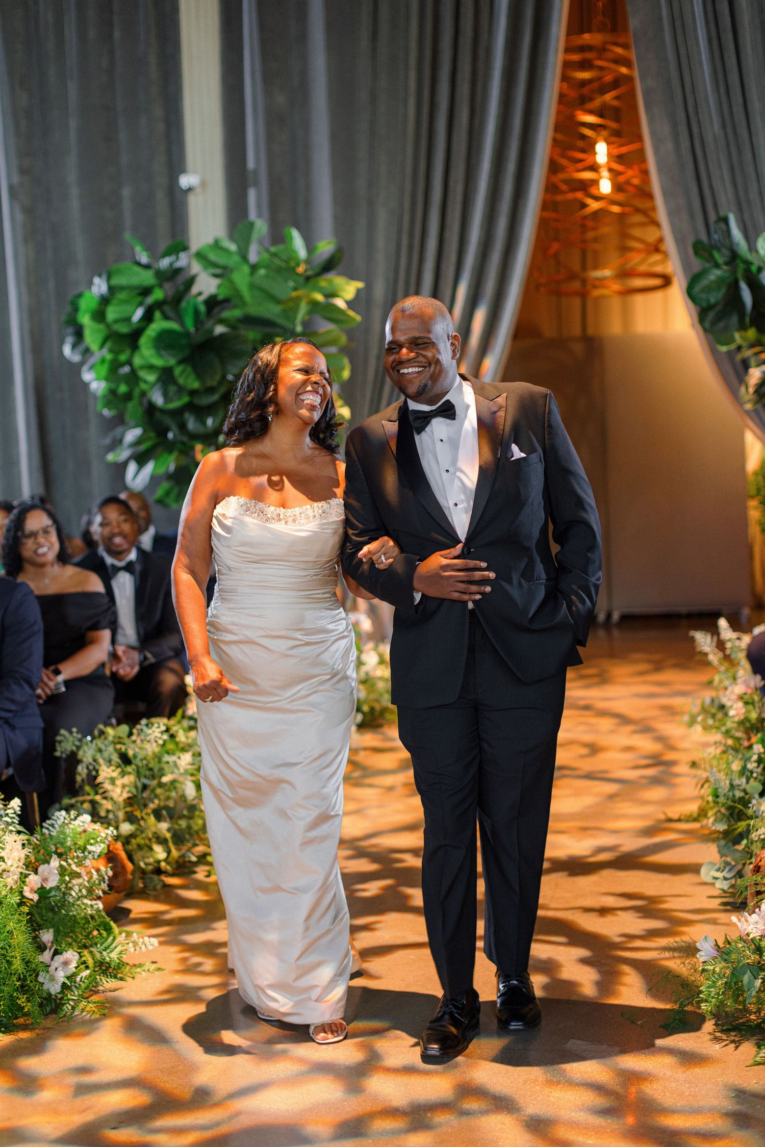 Wedding couple walks down the aisle together during ceremony with joyful expressions.