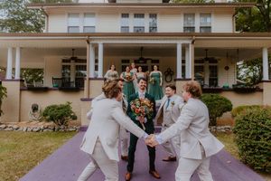 Wedding ceremony outside white building with purple walkway and columns.