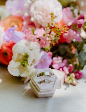 Wedding rings nestled among pink and white floral arrangements.