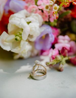 Diamond engagement ring and wedding band displayed with soft focus pink flowers.