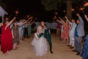 Wedding party and guests waving sparklers during nighttime celebration.