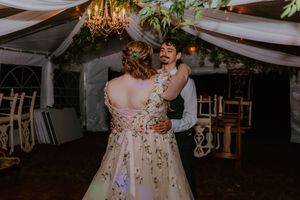 Wedding reception dance floor under white draped tent with hanging decor.