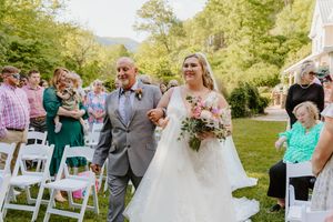 Outdoor wedding ceremony in a lush garden setting with white chairs and floral decorations.