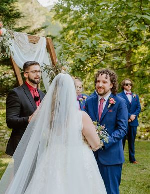 Wedding party celebrating during an outdoor ceremony with natural greenery backdrop.