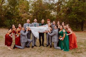 Wedding party posing outdoors in burgundy and emerald attire.
