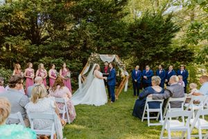 Garden wedding ceremony setup with white chairs arranged in rows under trees.