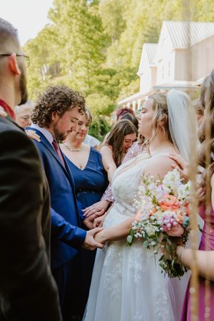 Intimate moment during outdoor wedding ceremony with floral bouquets and navy attire.