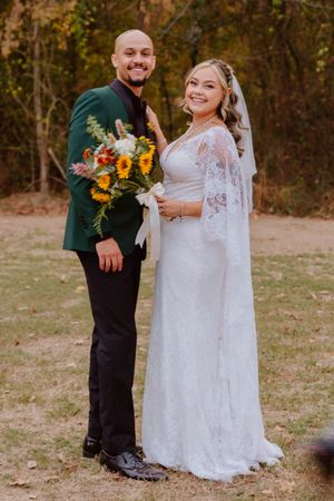 Wedding couple and wedding party in white lace and dark formal attire with sunflowers.
