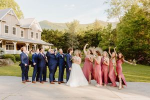 Wedding party lined up for fun group photos outside a country venue.
