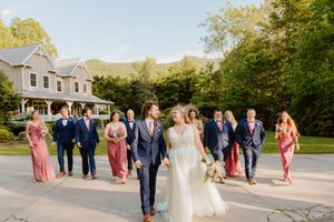 Wedding party in navy and pink attire posing for formal photos outside venue.