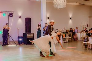 Wedding reception dance floor with guests performing choreographed moves in an elegant white ballroom.