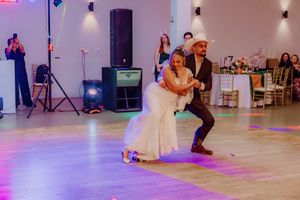 Couples dancing on a spacious ballroom floor with purple mood lighting and decorative wall sconces.