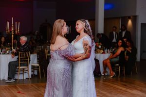 Wedding attendees in formal attire dancing together during an evening reception.